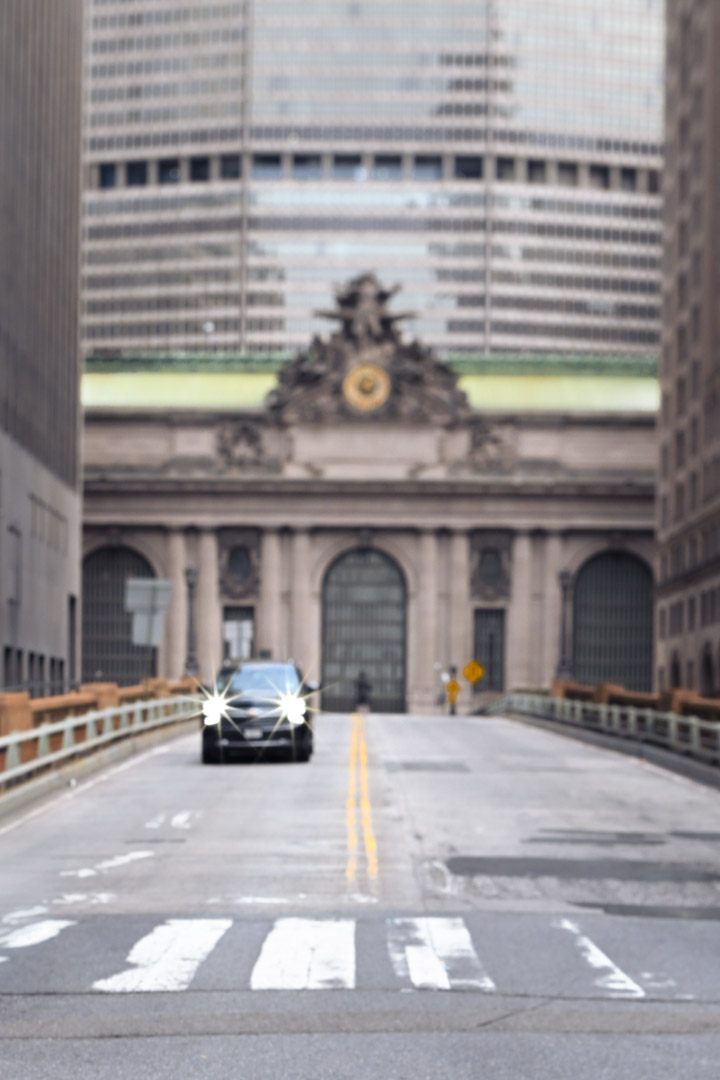 A taxi approaches Grand Central Terminal between tall buildings